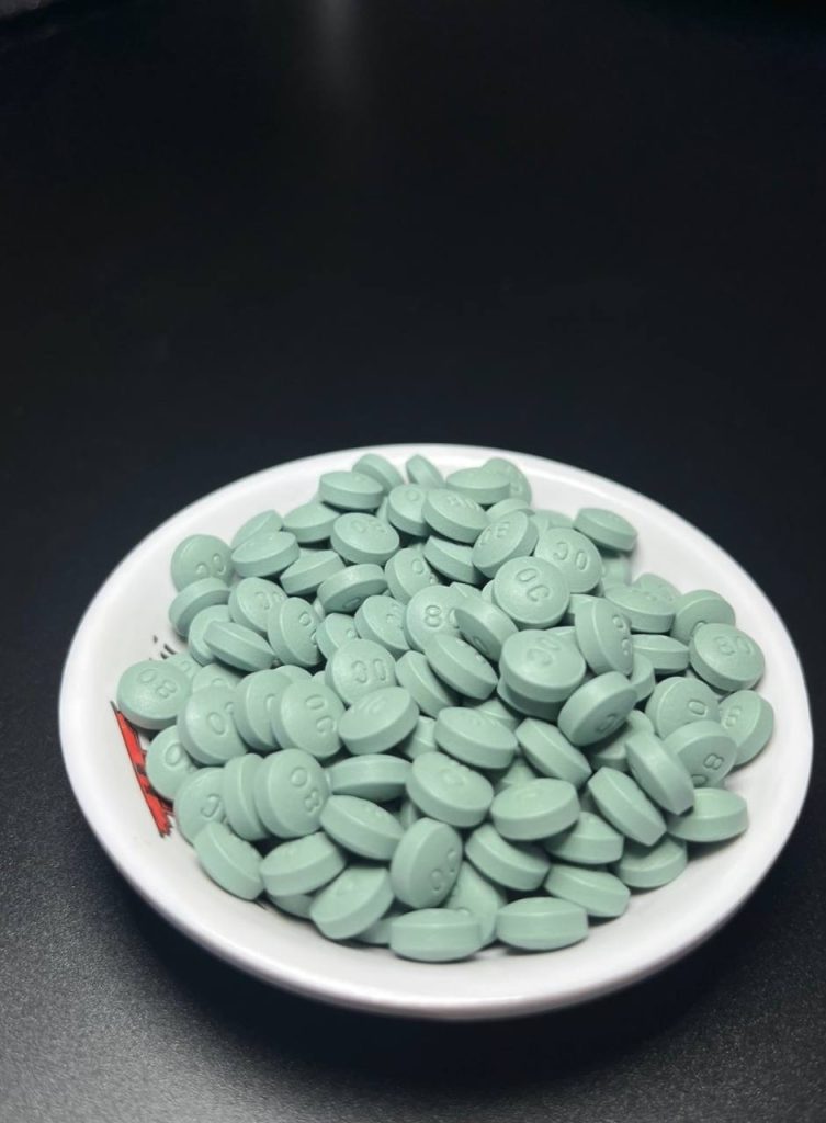 Green OxyContin 80mg pills labeled OP 80 in a jar – real extended-release oxycodone tablets